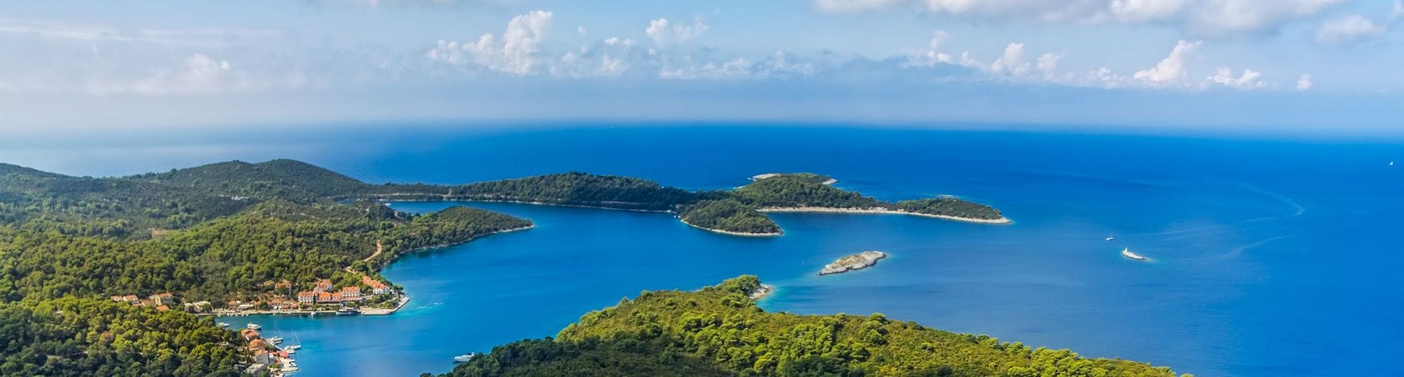 Beautiful view of the Dubrovnik sailing route near Mljet, Croatia – A yacht sailing in the clear blue waters, with the lush greenery of Mljet Island and its stunning coastline providing a picturesque backdrop.