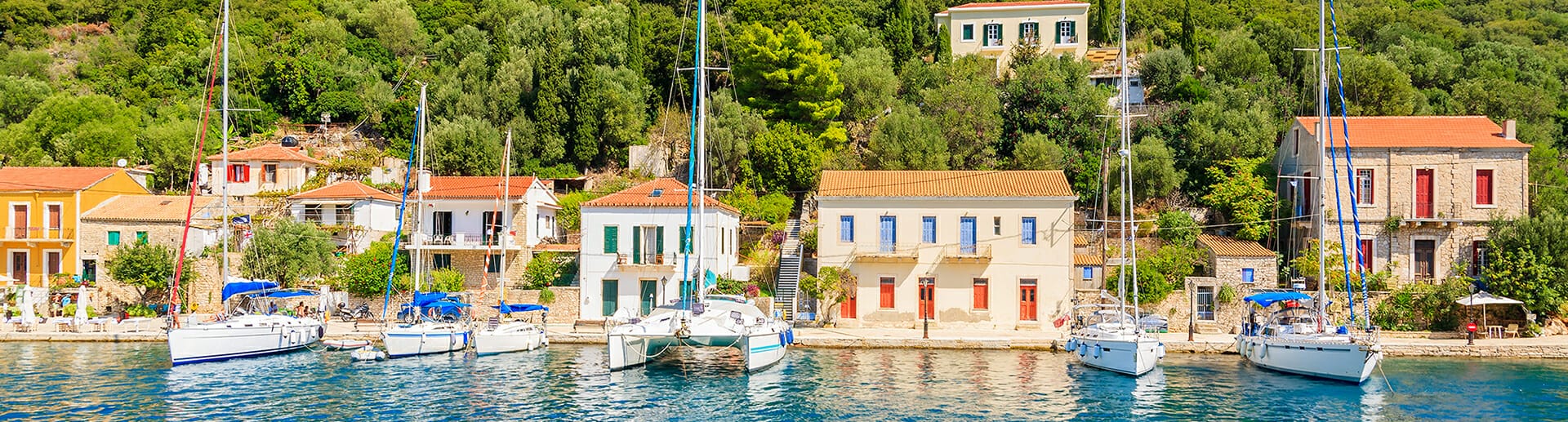 Scenic view of the Southern Ionian sailing itinerary near Kioni, Ithaca, Greece – A yacht anchored in the tranquil bay, surrounded by lush greenery and the charming village of Kioni, set against a backdrop of stunning coastal landscapes.