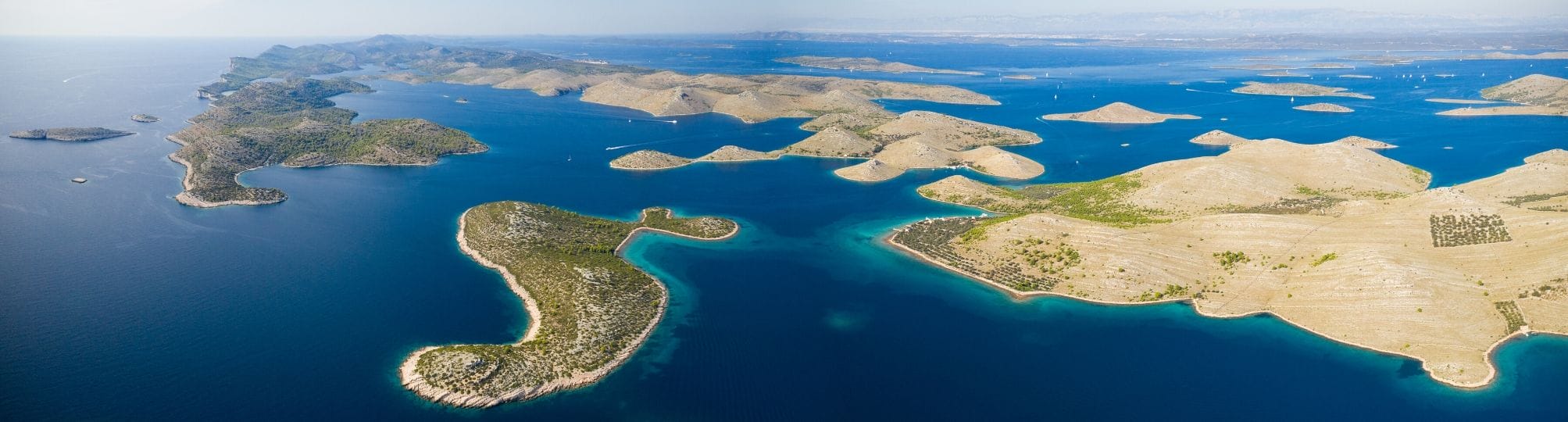 Stunning aerial view of Kornati National Park in Croatia – A yacht sailing through the pristine waters, surrounded by the unique rocky islands and vibrant marine life that characterize this beautiful national park.